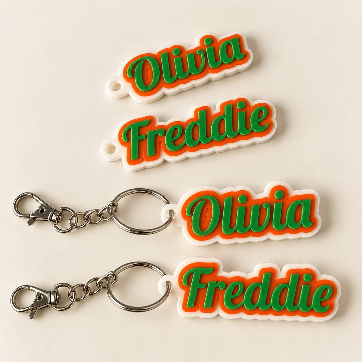 Personalised Olivia and Freddie name keyrings with green lettering, orange outlines and white backing.